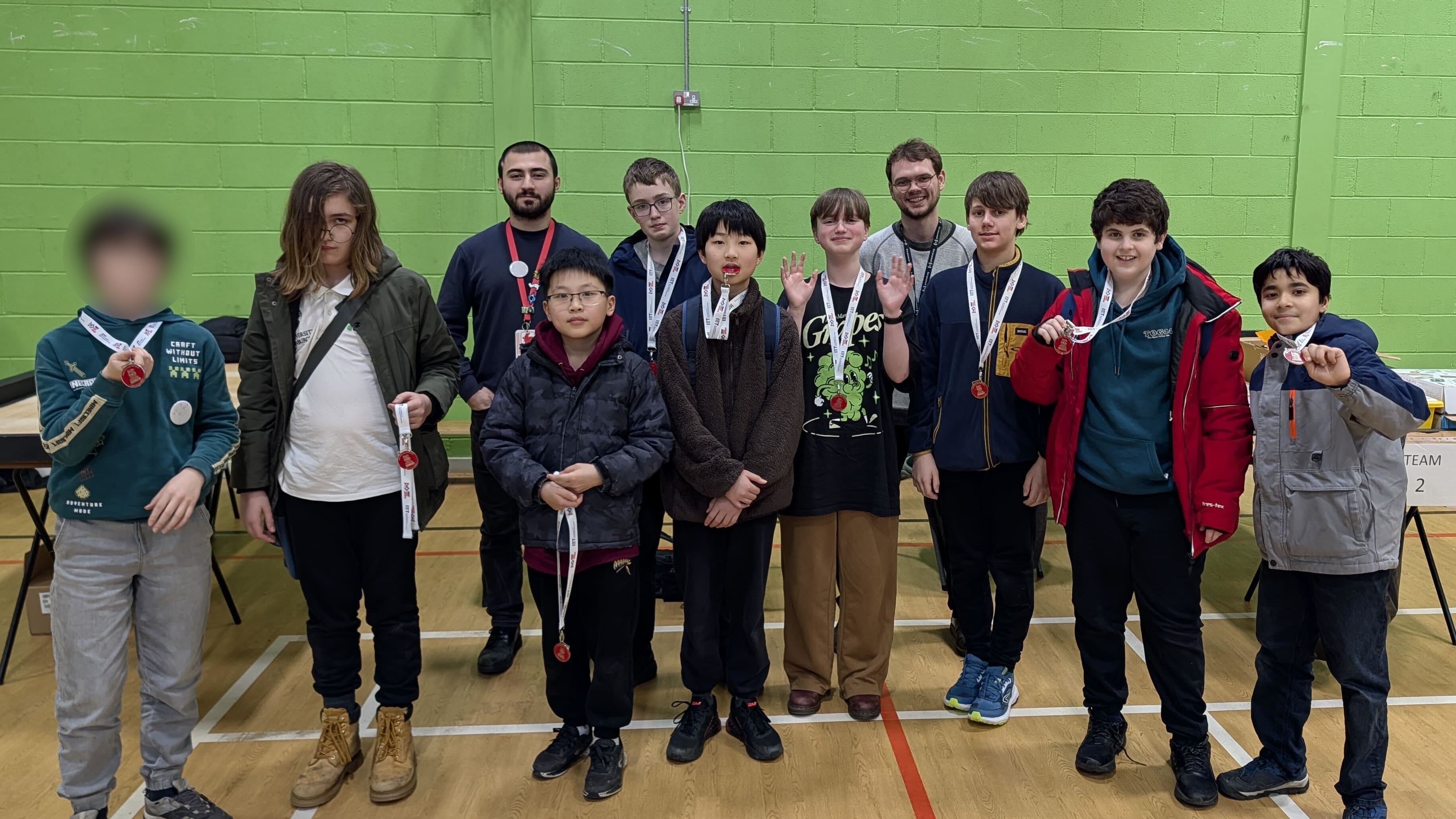All Prewired participants of the 2025-2026 team and two mentors lined up at the competition, showing off medals