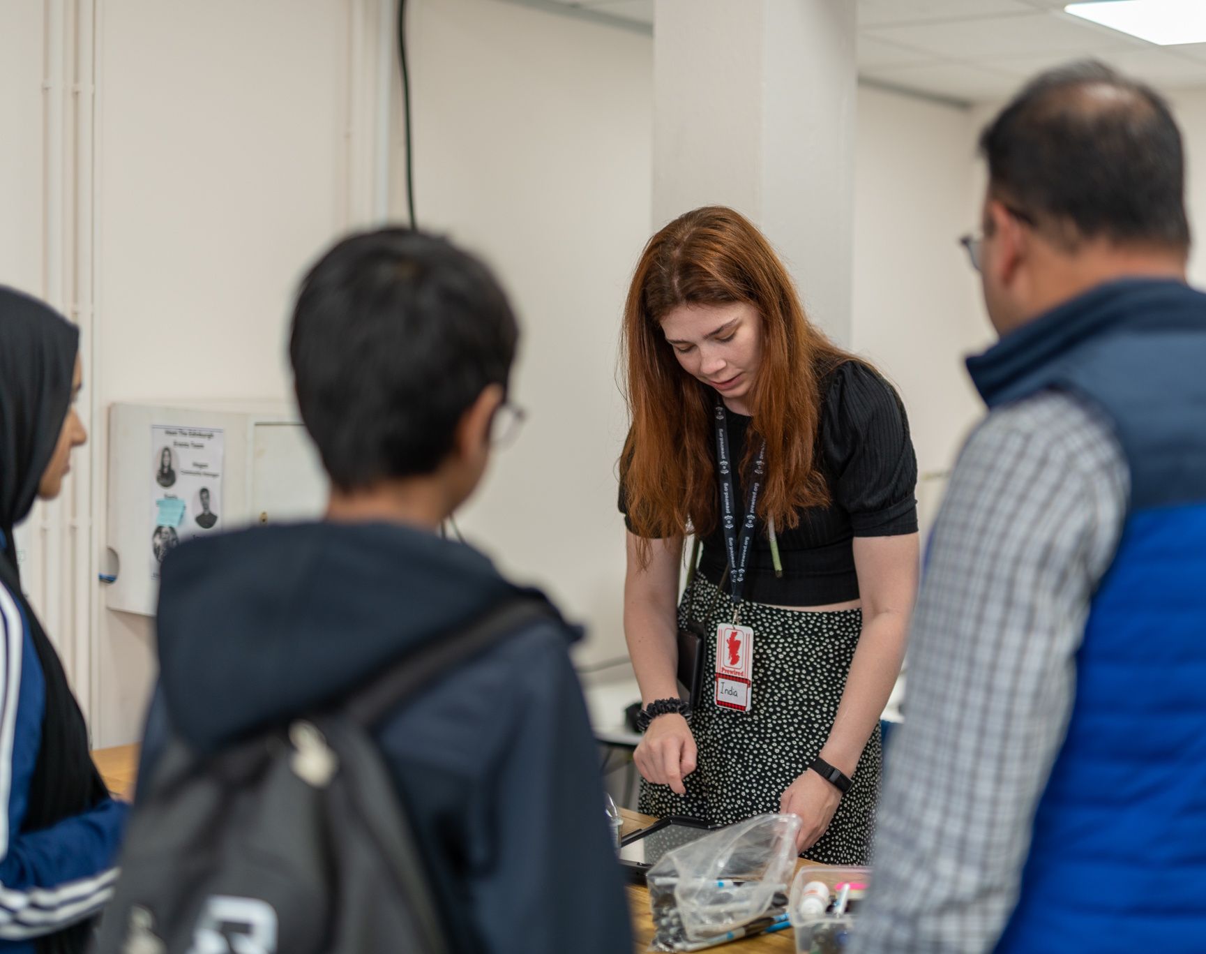 A mentor is checking in two attendees and their parent at the front desk
